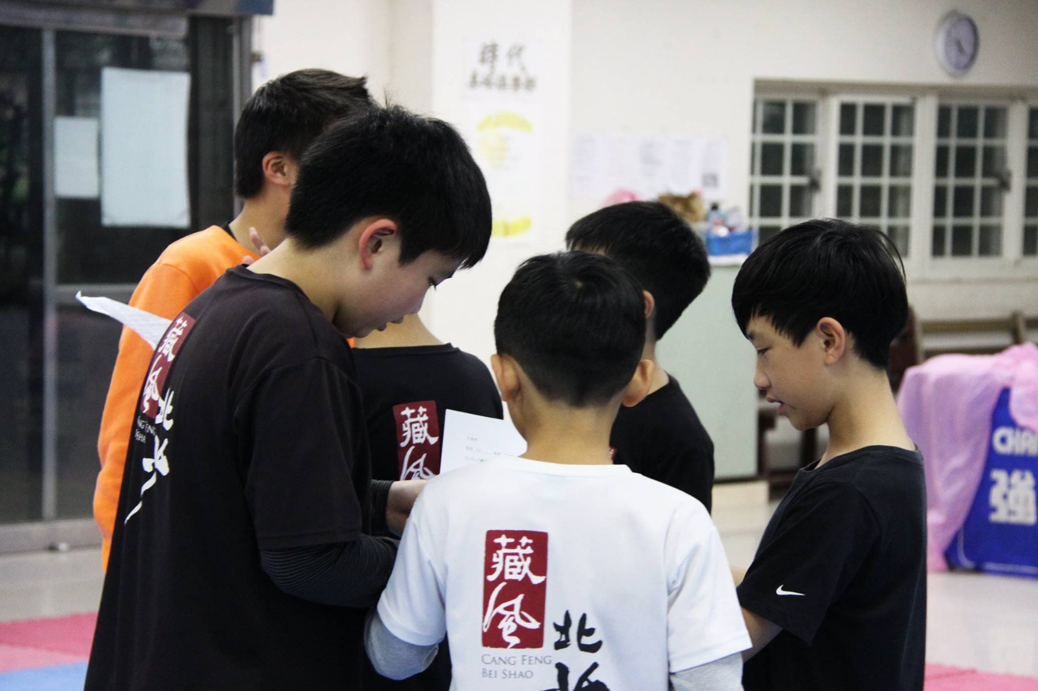 學員圍在桌邊查看資料，共同準備武林大會。