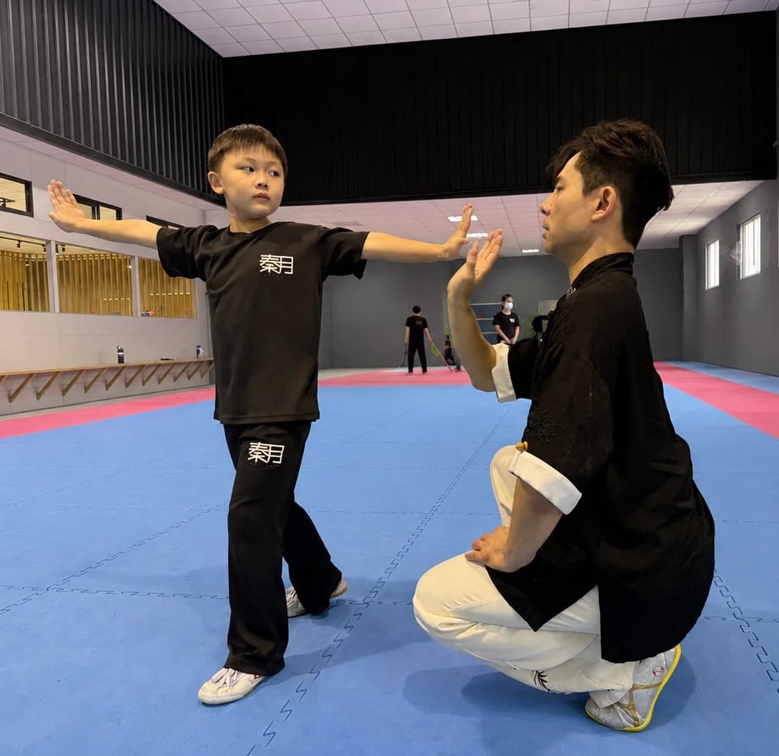秦月教練近距離觀察並引導兒童學員完成個別動作練習